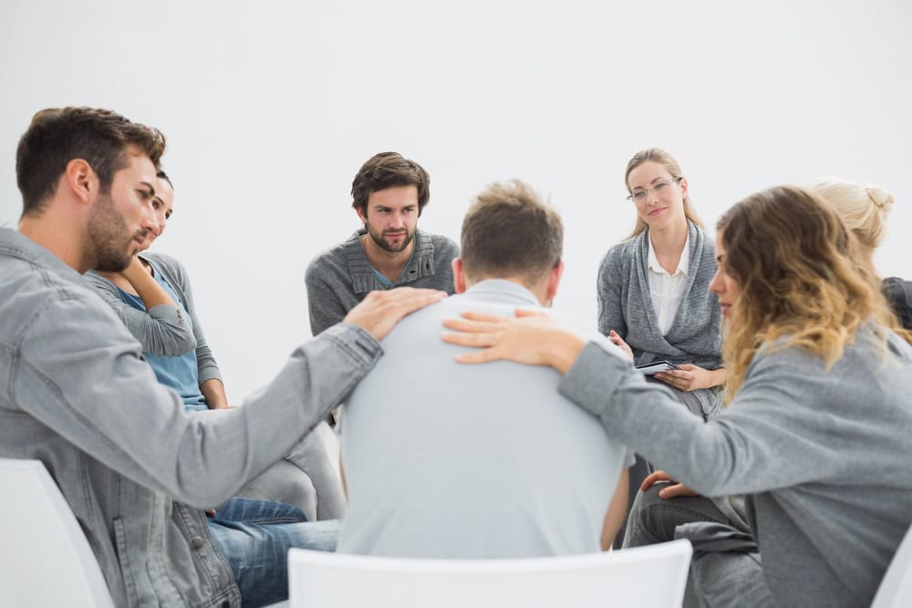 A group of individuals consoling a depressed man