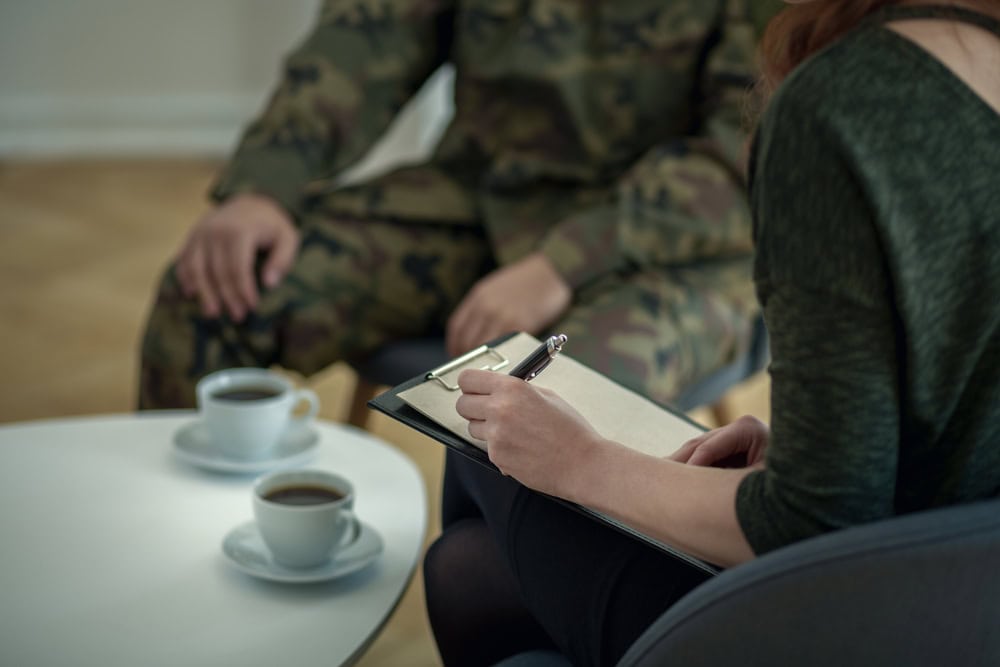 Cropped image of a soldier and psychologist during a cognitive processing therapy session